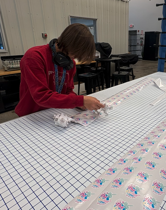 student leaning over a table while working on stickers