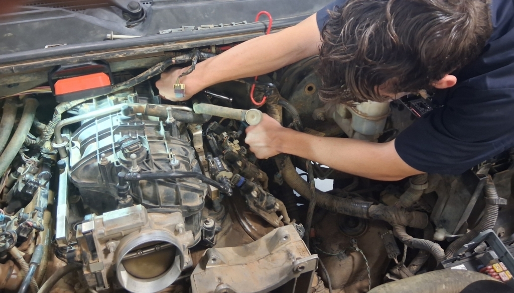 Automotive student Titus Moncrief installs bolts on the instale manifold on a 2007 Chevy Tahoe.