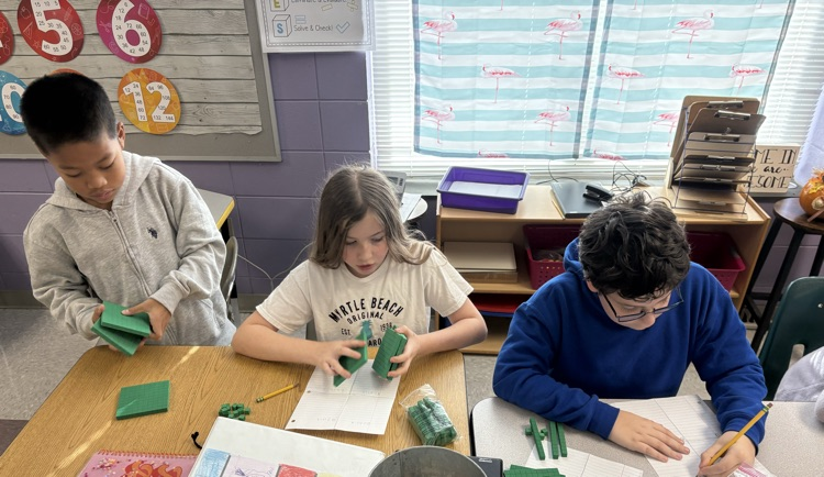 students dividing decimals using base ten blocks to regroup whole numbers into tenths and hundredths