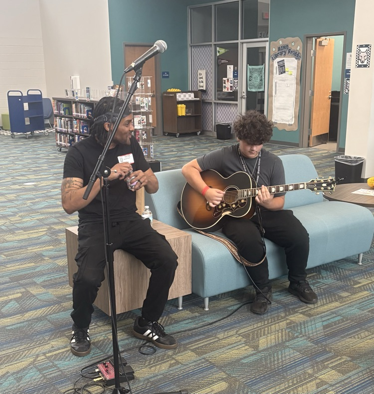 students listening to musician playing guitar 