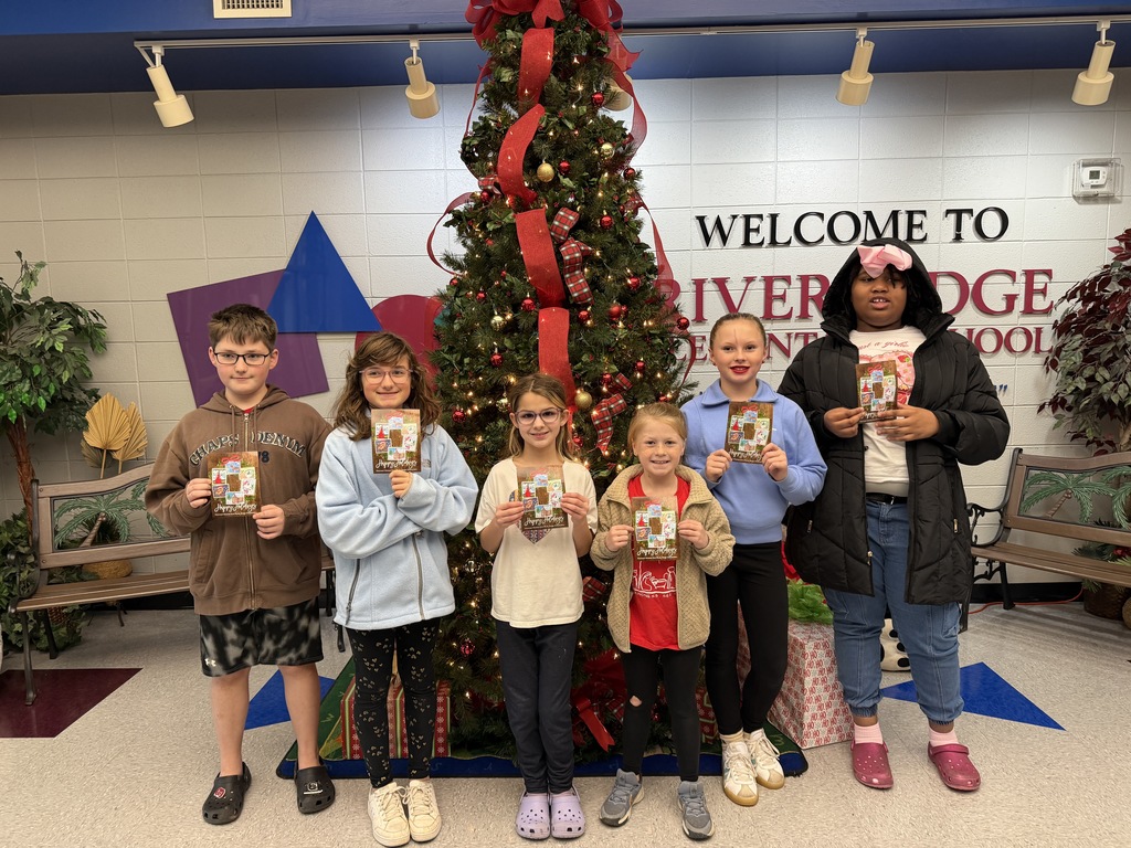 students in front of Christmas tree holding the school's holiday card