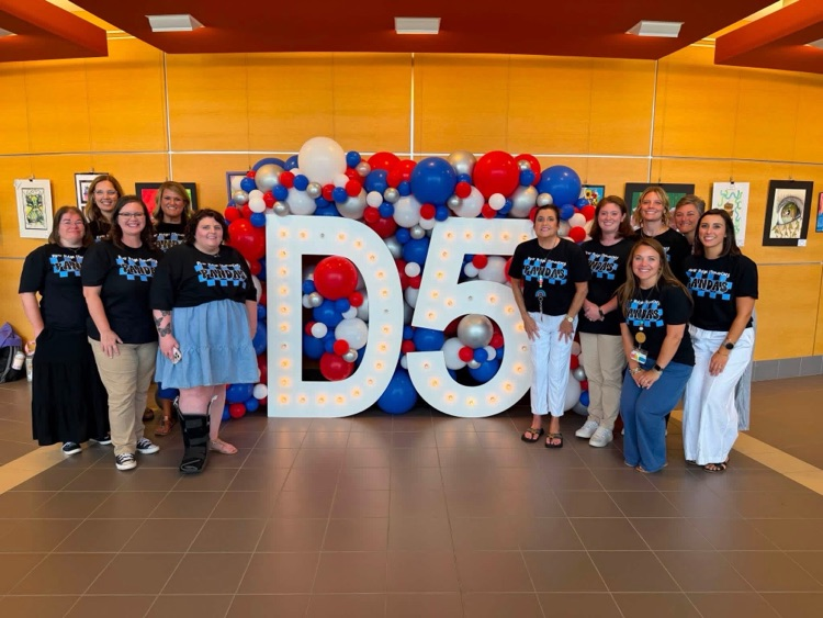 Our Special Education team smiling in front of a display of balloons and a large letter D and number 5