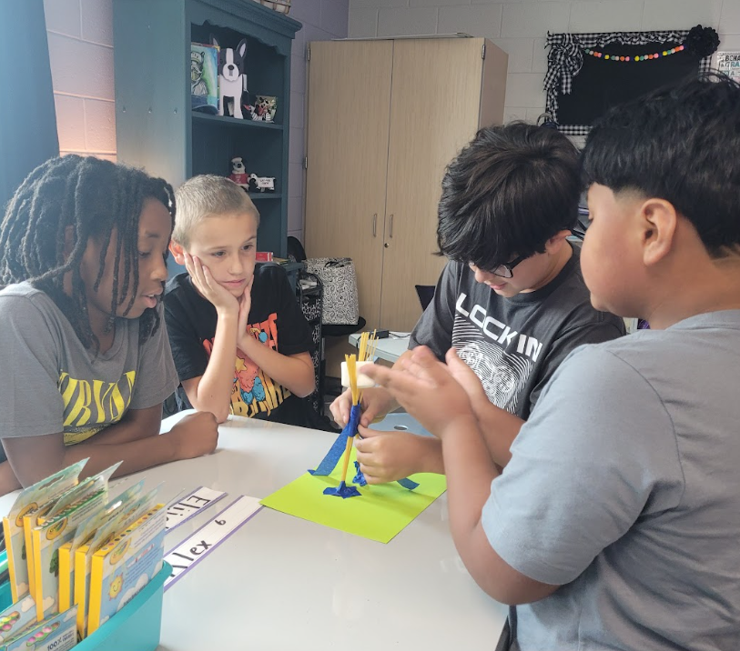 This image includes a picture of students working together to build a spaghetti tower.