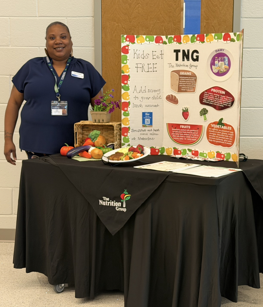 This image is a picture of the cafeteria manager posing with a display about healthy eating.
