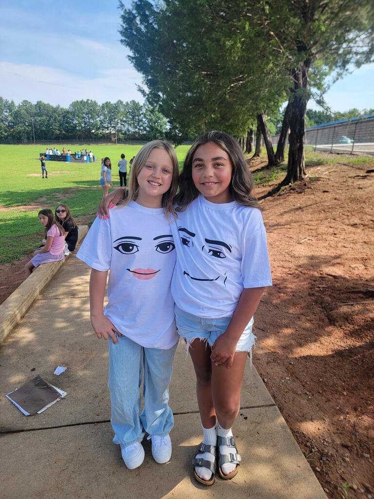 2 girls wearing similar shirts out on the playground