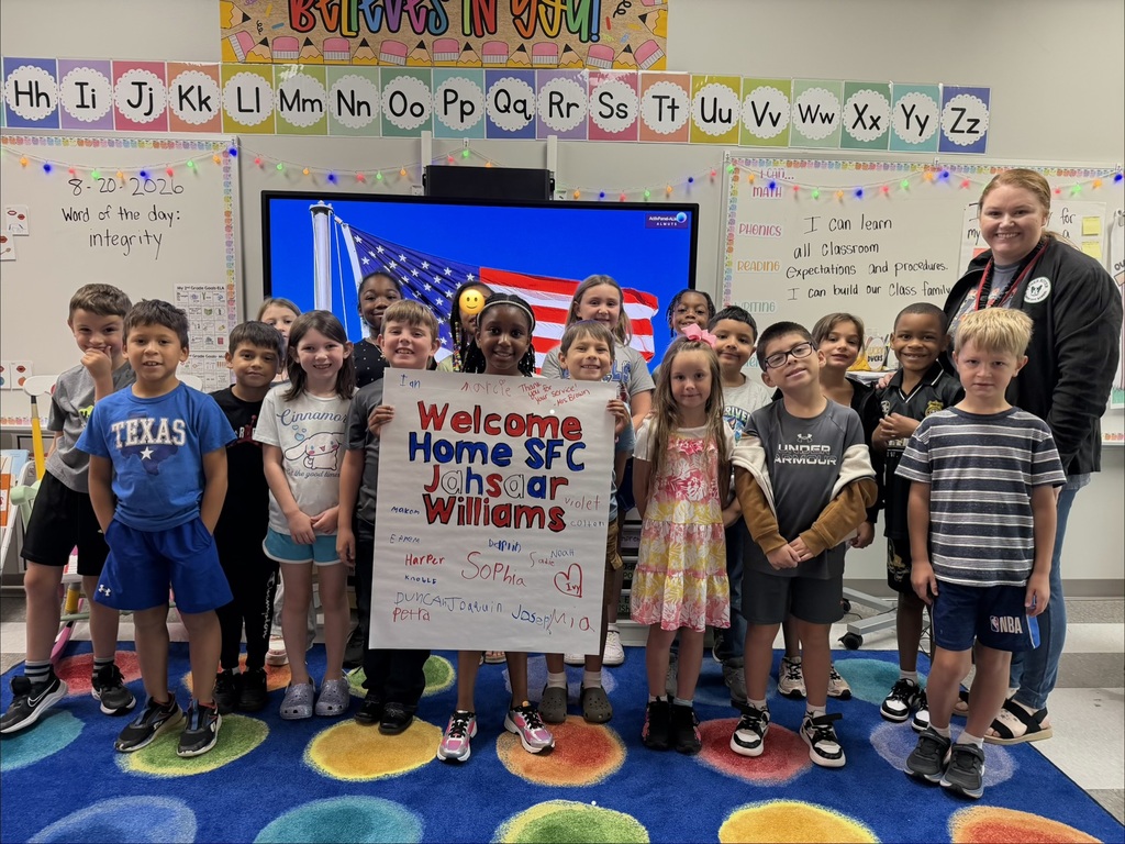 This is a picture of a class welcoming home a parent who has been away with the military with a poster.