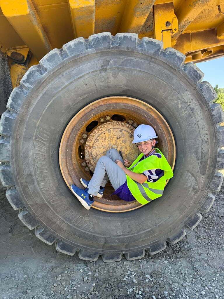 student sitting in bulldozer wheel