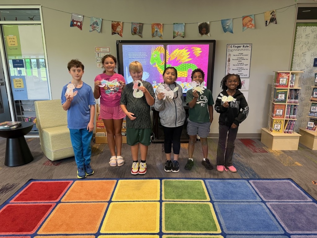 This image shows fourth graders holding up the alebrijes that they created for Hispanic Heritage Month..