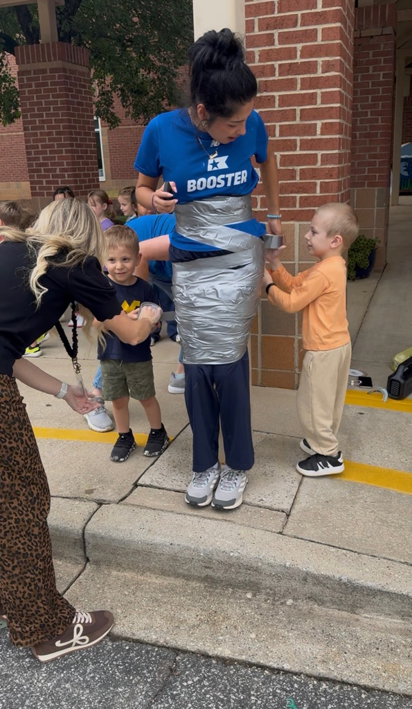 students using duct tape to tape the legs of an adult to a ploe