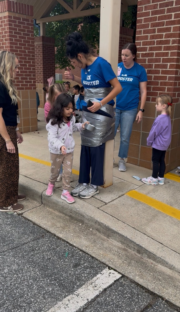 students using duct tape to tape the legs of an adult to a p