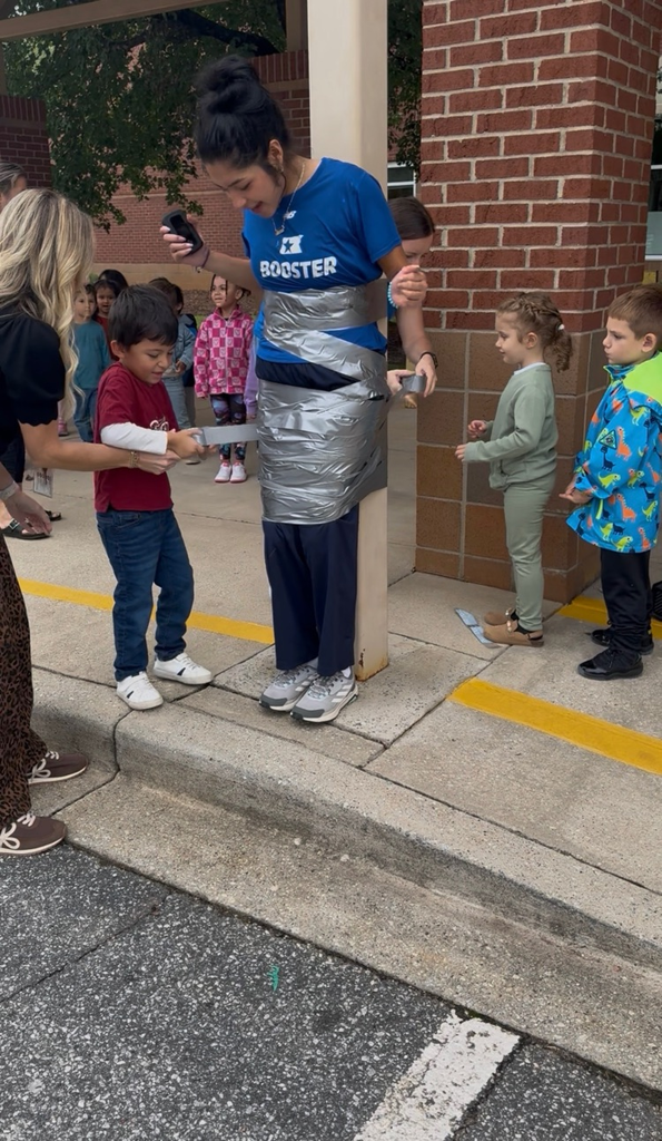 students using duct tape to tape the legs of an adult to a p