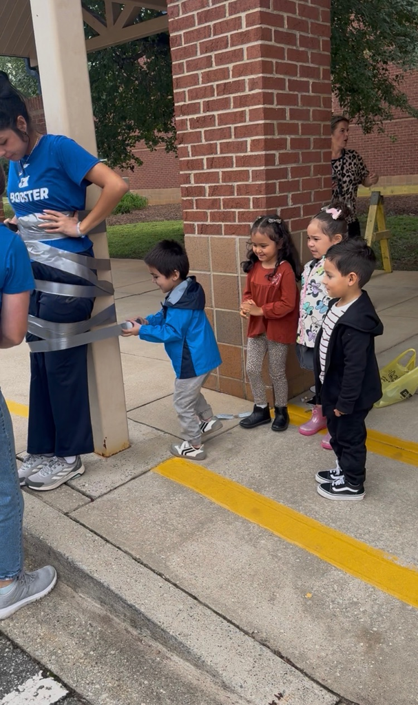 students using duct tape to tape the legs of an adult to a p