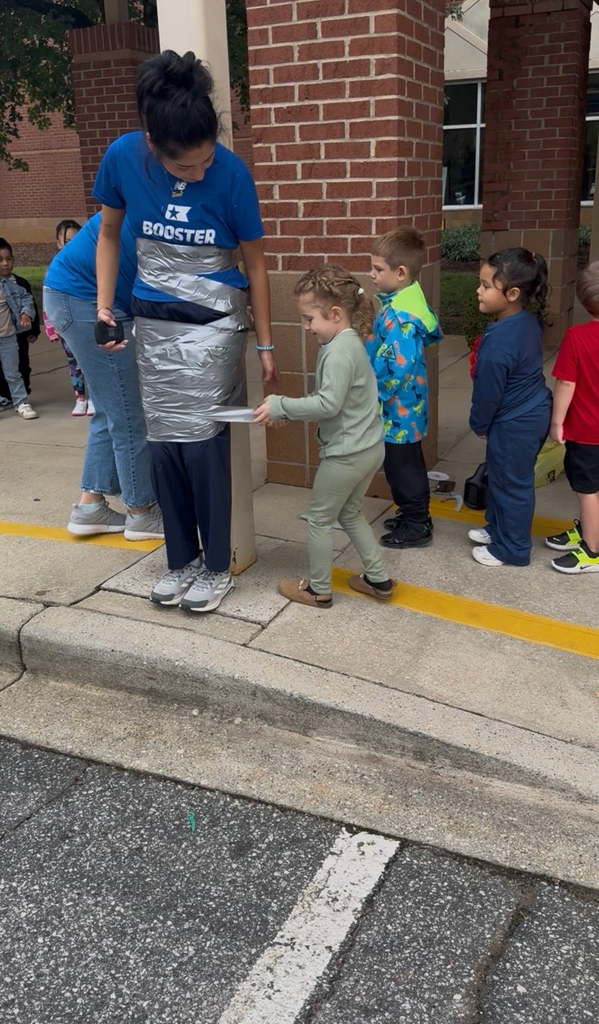 students using duct tape to tape the legs of an adult to a p