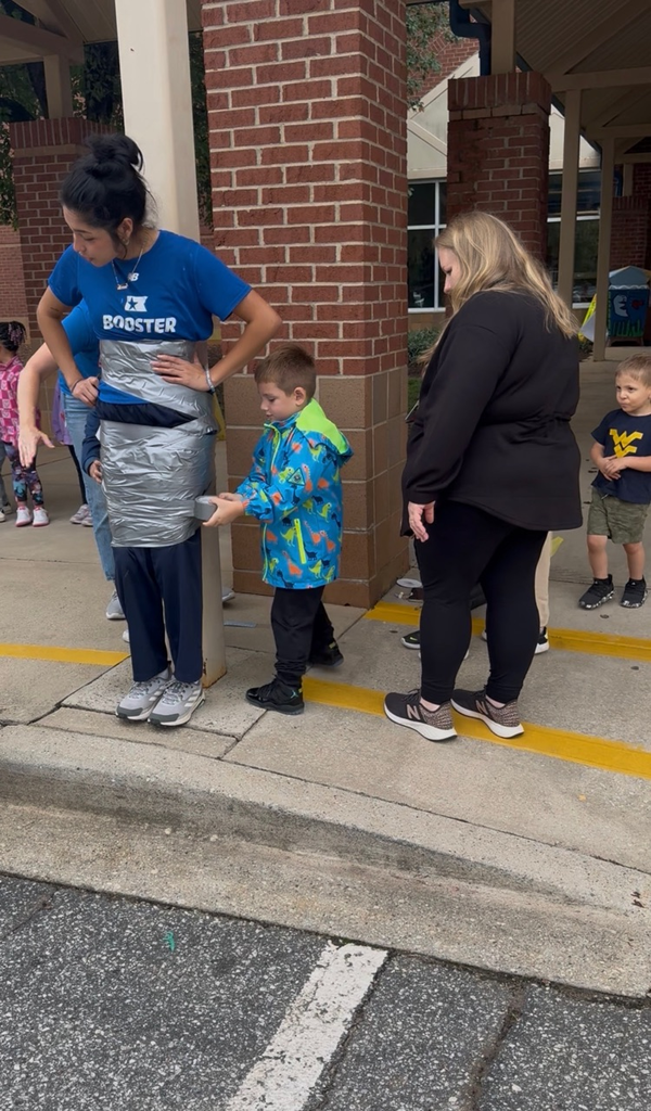 students using duct tape to tape the legs of an adult to a p