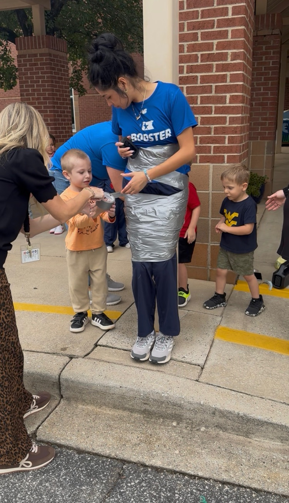 students using duct tape to tape the legs of an adult to a p