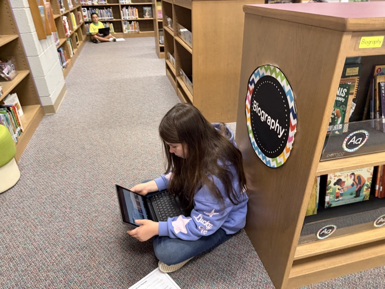 students in the library recording podcasts on laptops