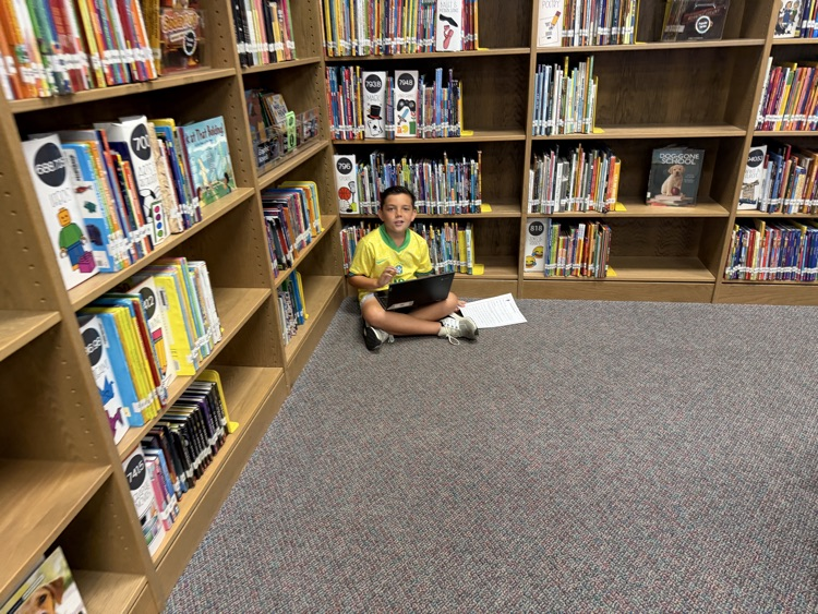 students in the library recording podcasts on laptops