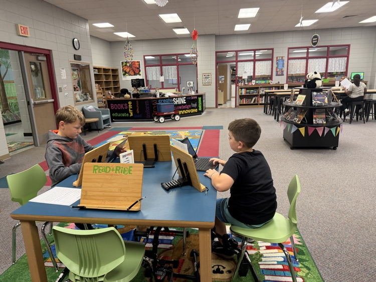 students in the library recording podcasts on laptops