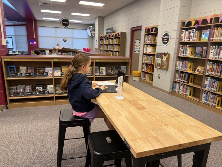 students in the library recording podcasts on laptops