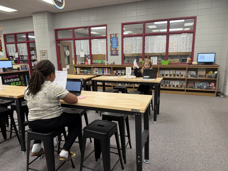 students in the library recording podcasts on laptops