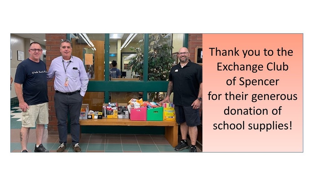 Three men standing in front of boxes of school supplies