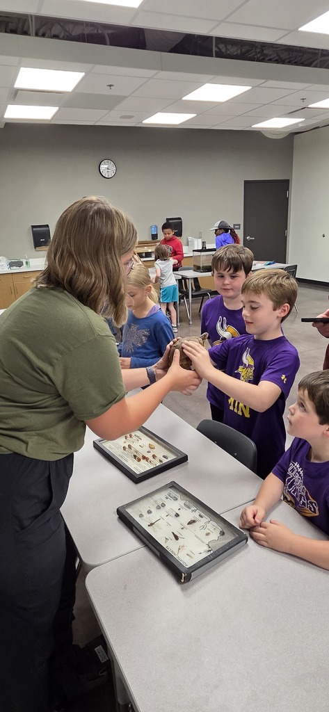 An elementary student holding a turtle with classmates around them.