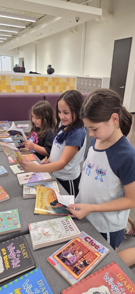Elementary students looking at books.