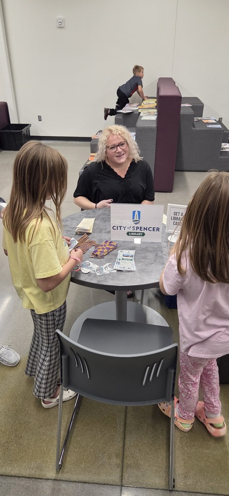 Elementary students speaking with a librarian about library cards.