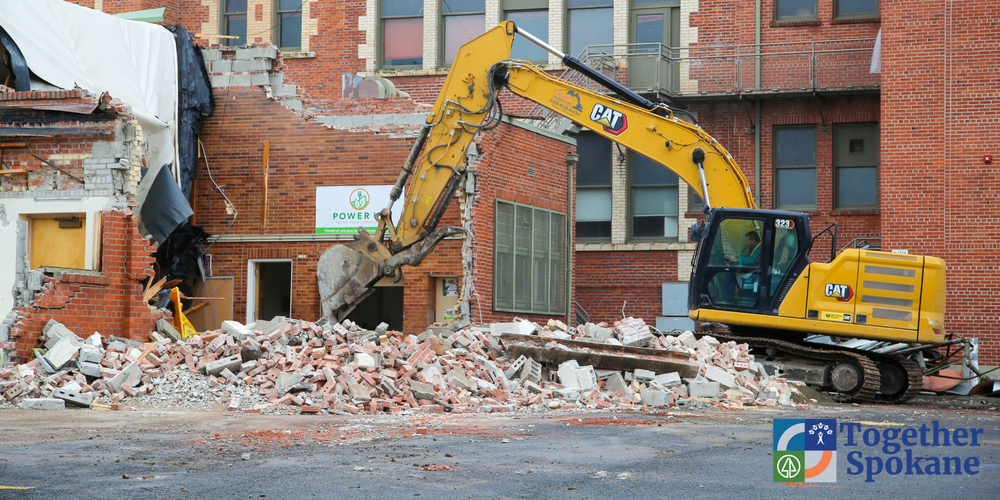 An excavator demolishes a brick building