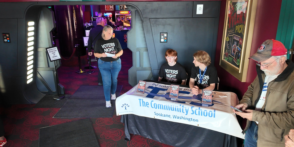 Students and teachers from The Community School table at an event to share about Voters Night Live.