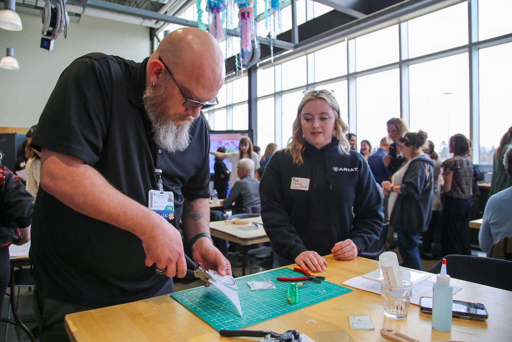 Man cuts glass while female student looks on.