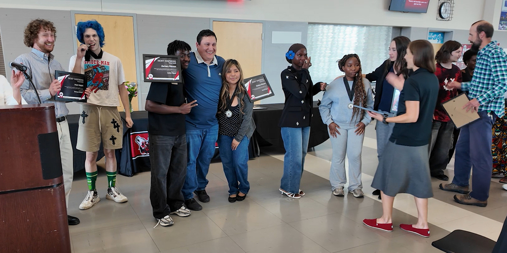 North Central High School students holding plaques and wearing medals smile with teachers.