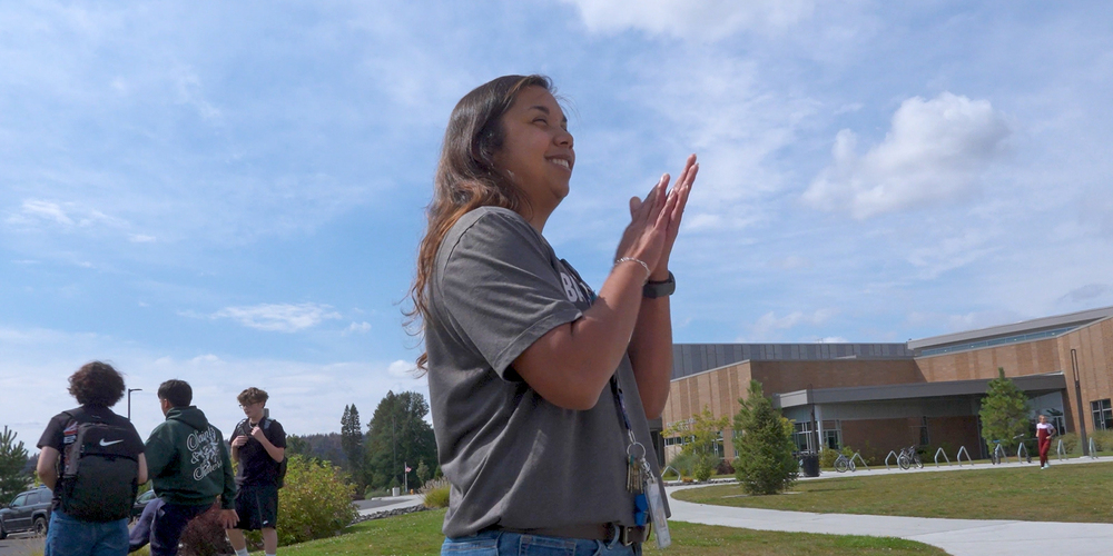 Tatriana Muravez smiles and claps outside Flett MiddleSchool.