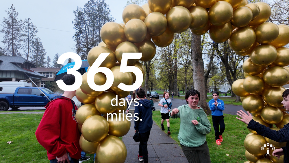 Hutton elementary student Harry run his 365 1-mile run in a  row under a golden balloon arch.