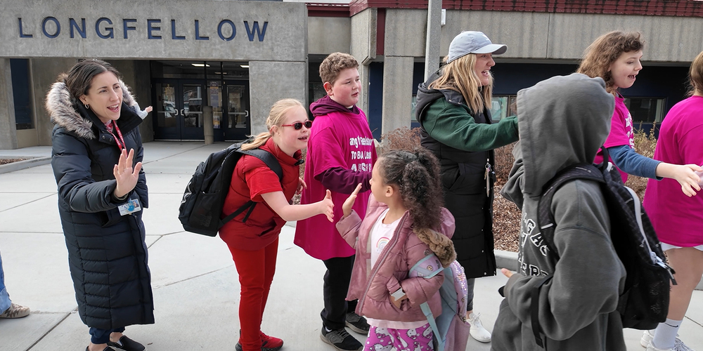Longfellow students and staff give high fives to students outside the school.