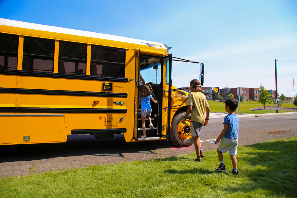 Children getting on a yellow school bus.