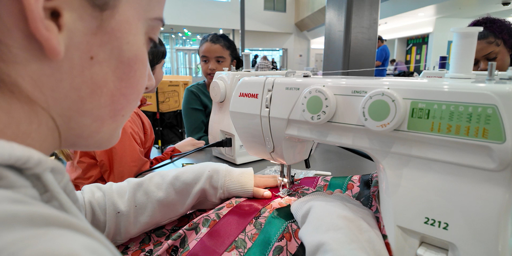 Students use sewing machines to create ribbon garments at Flett Middle School.