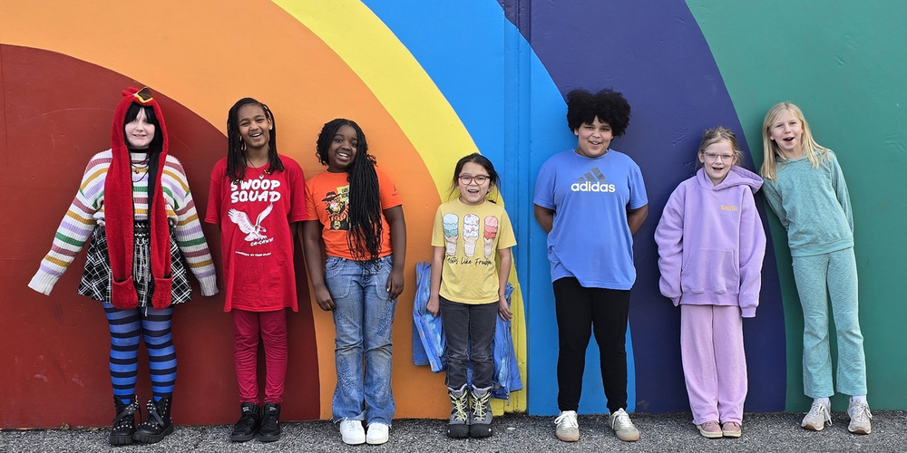 Students smiling in front of a wall