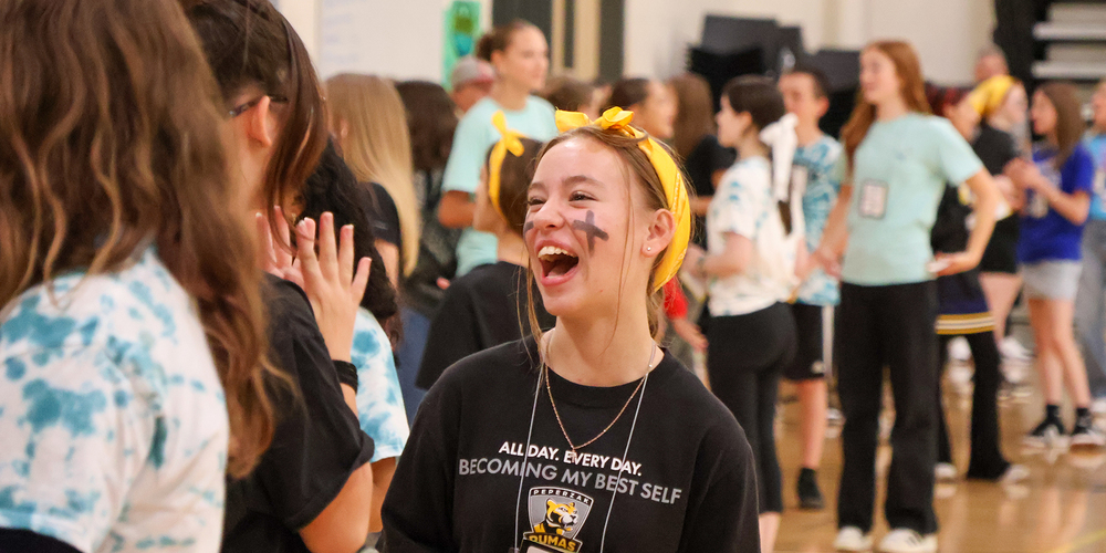 A Peperzak student laughs and smiles with other students in a school gym.