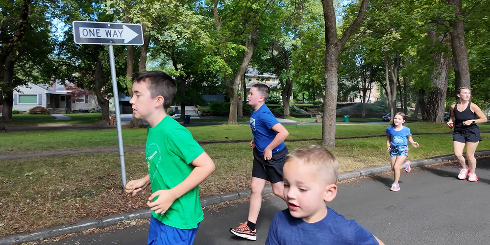 Children and adults run in a neighborhood together.
