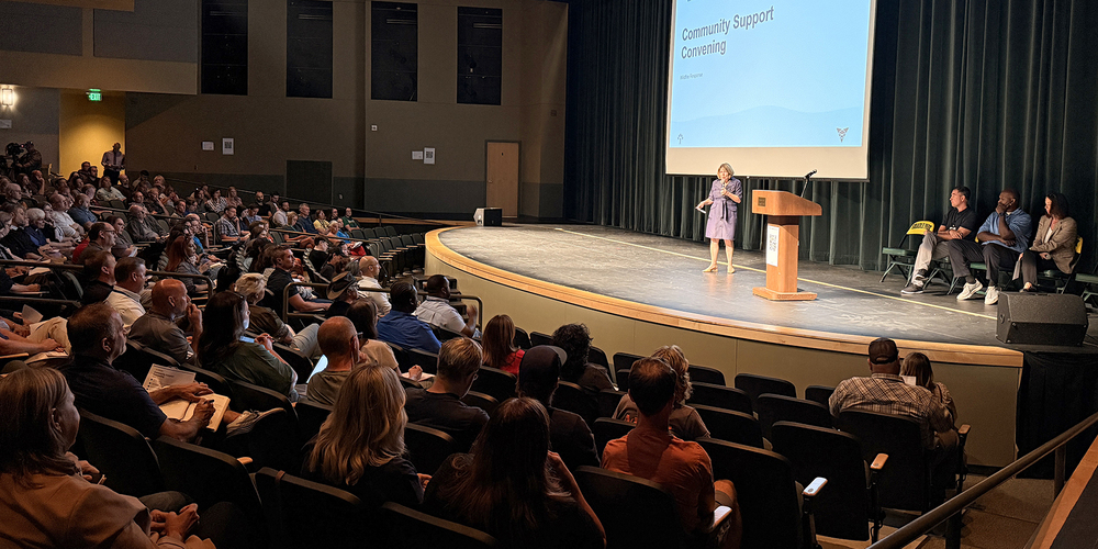 Mayor Lisa Brown speaks on stage to an auditorium of community organization leaders.