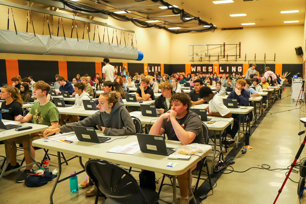 Dozens of students sit at computers in a large room.