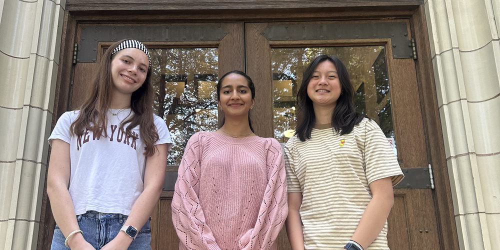 Three high school seniors pose in front of their school