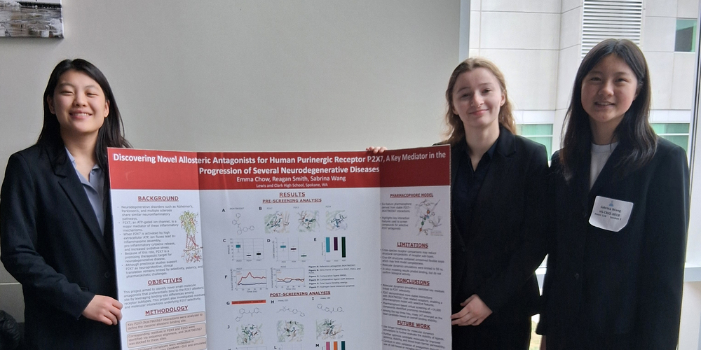 Three Lewis and Clark High School students smile with their science fair project posterboard.