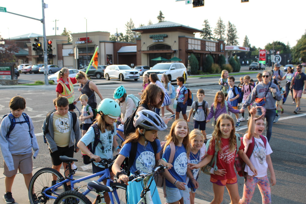 Large group of students using a crosswalk to walk to school.