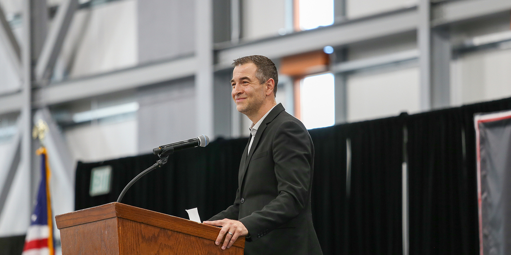 Superintendent Adam Swinyard smiles as a lectern.