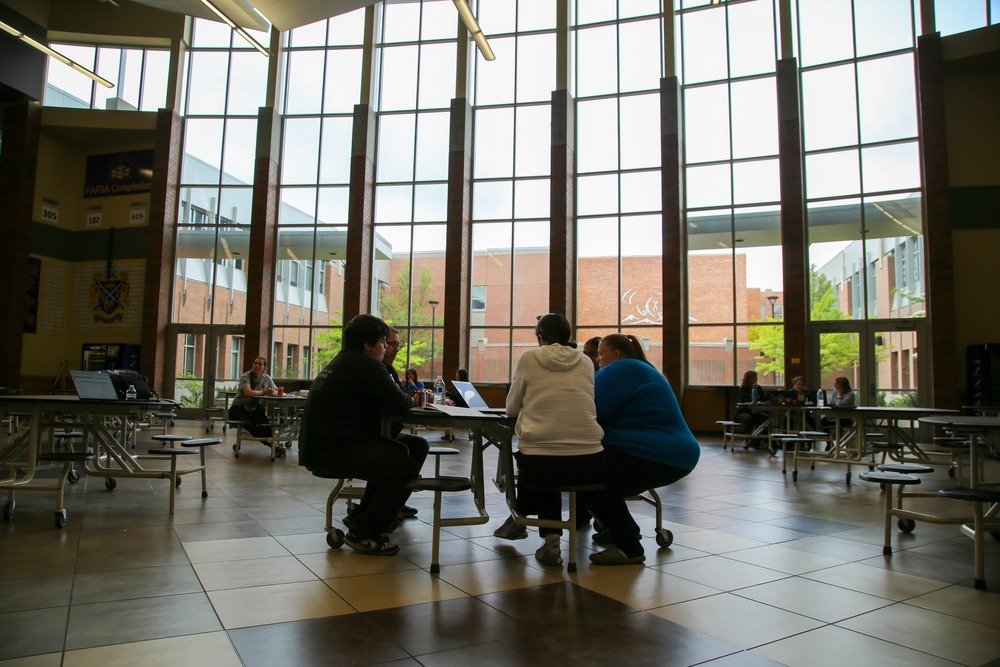 A family sitting with staff at a table in the Rogers High School commons.