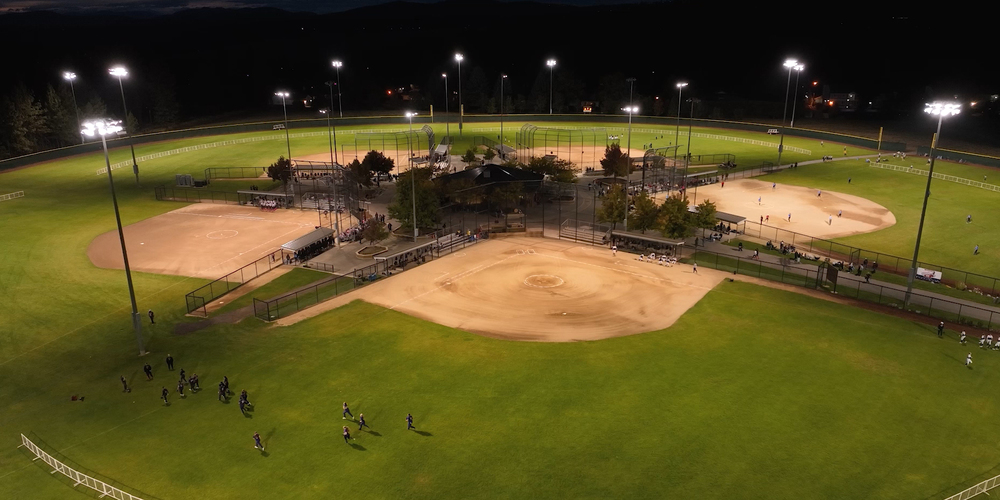 A softball game played under stadium lights.