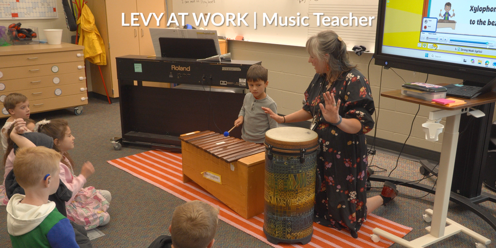 Music teacher Kaitlyn Webster and a student play a xylophone and a drum to instruct other students.