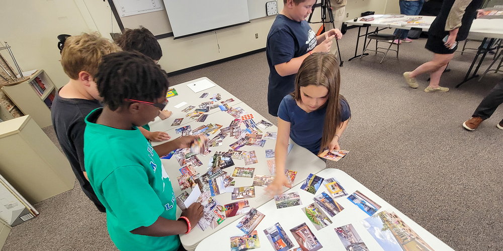 Elementary students pick from assorted photographs to help display their design ideas for a new school.